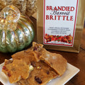Anette's Chocolates Brandied Harvest Brittle with packaging and decorative elements on a wooden surface.