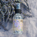 Bottle of Lavender Water Botanical Mist with lavender flowers on a textured surface