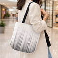 Woman carrying a black and white striped tote bag in a mall.