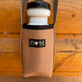 Woven bottle holder with a white water bottle on a wooden surface