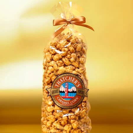 Bag of Thatcher's Caramel Corn with a gold bow on a gold background