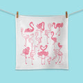 White towel with pink flamingo pattern hanging on a clothesline against a blue background