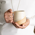 Person holding a ceramic mug with a plain background