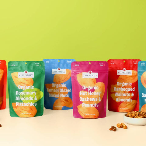 Assorted bags of organic snacks on a light surface with a green background