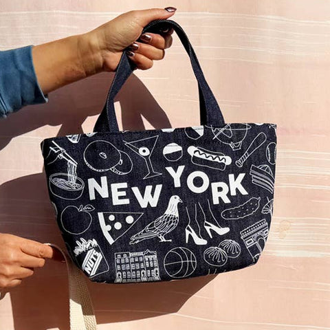 Two tote bags with 'New York' design held by a person against a light pink background