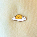 Cartoon-style fried egg with a smiling face on a beige fabric background