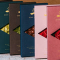 Five chocolate boxes with different colors and designs on a textured surface.