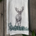 White towel with a black deer illustration on a wooden surface