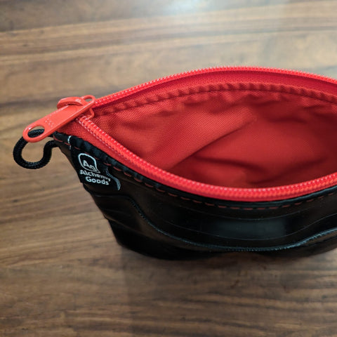 Black pouch with red zipper on a wooden surface