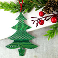 Christmas tree-shaped ornament made from a green circuit board on a white surface with greenery and berries.