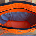 Open orange bag with blue interior on a wooden surface