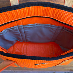 Open orange bag with blue interior on a wooden surface
