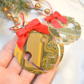 Hand holding a Christmas ornament made from a circuit board with a red bow, surrounded by festive decorations.