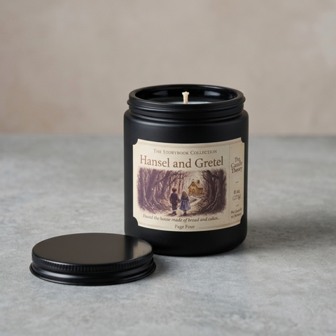 Candle in a black tin with a label featuring 'Hansel and Gretel' on a gray surface.