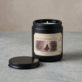 Candle in a black jar with a label on a gray surface