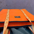 Orange mat with gold border on a gray surface