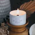 Candle with a label on a wooden holder against a dark background