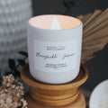 Candle with a label on a wooden stand, surrounded by decorative elements.