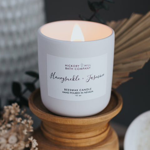 Candle with a label on a wooden stand, surrounded by decorative elements.