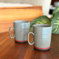 Two ceramic mugs with textured finish on a wooden surface.