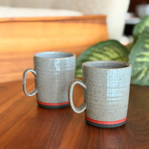 Two ceramic mugs with textured finish on a wooden surface.