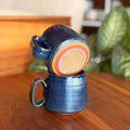 Blue ceramic mug with colorful interior on a wooden surface