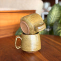Two ceramic mugs stacked on a wooden surface with a blurred background