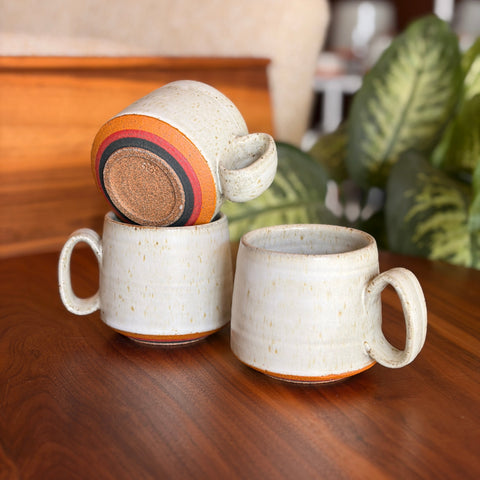 Set of ceramic mugs on a wooden surface with a blurred indoor background