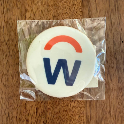 Round white object with red and blue logo on a wooden surface