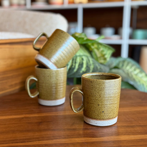 Three ceramic mugs on a wooden surface with a blurred background