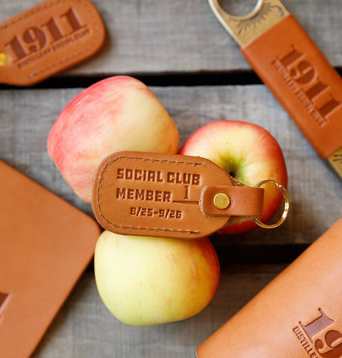 Leather keychain with 'Social Club Member' text on apples