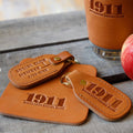 Brown leather keychain and tag with '1911 Distillery Social Club' branding on a wooden surface.