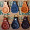 Set of six leather keychains with engraved design on a textured surface.