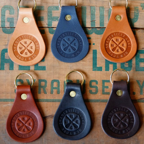 Set of six leather keychains with engraved design on a textured surface.
