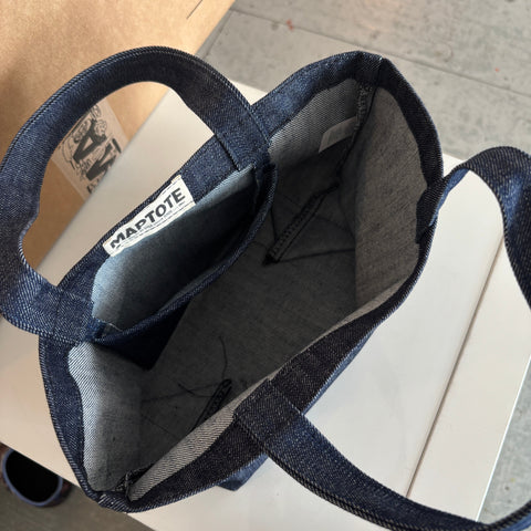 Blue denim bag with a visible brand label on a wooden surface