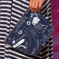 Person holding a blue clutch with white graphics and 'California' text against a colorful background