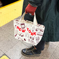Person holding a tote bag with 'New York' text and graphics on a subway platform.