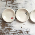 Three small ceramic bowls with heart designs on a rustic wooden surface