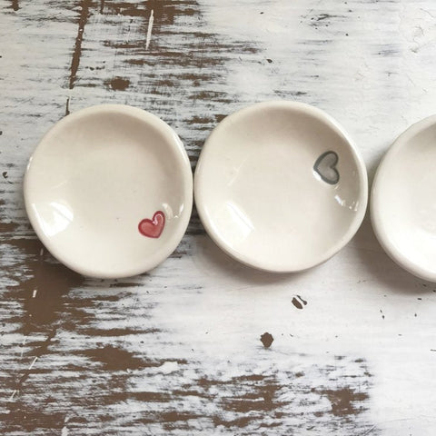 Three small ceramic bowls with heart designs on a rustic wooden surface