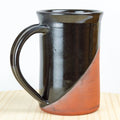 Black and brown ceramic mug on a wooden surface with a white background