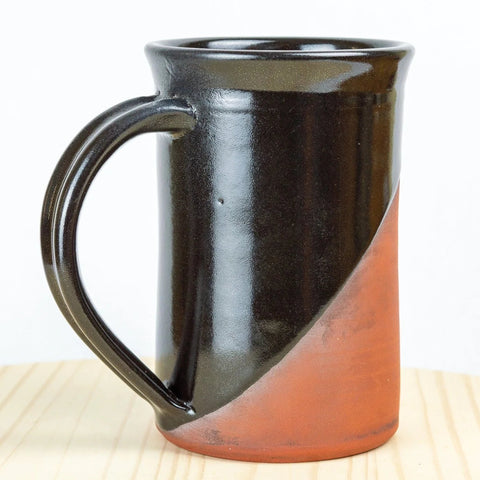 Black and brown ceramic mug on a wooden surface with a white background