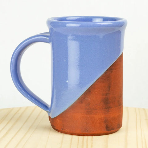 Ceramic mug with blue top and brown bottom on a light wooden surface