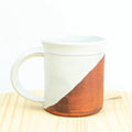 White mug with a brown accent on a light wooden surface