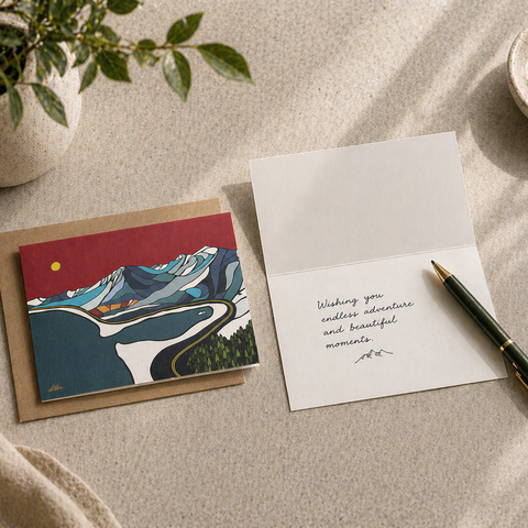Greeting card with whale illustration on a beige surface with a pen and plant.
