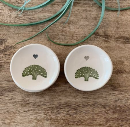 Two white ceramic dishes with green leaf patterns on a wooden surface.