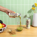 Person pouring Laurel's matcha into a glass on a kitchen counter with a green tiled wall.