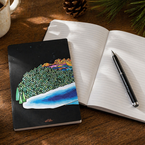 Notebook with a nature-themed cover, open to a blank page on a wooden surface with a cup and pen.