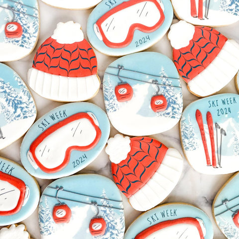 Decorative cookies with ski week 2024 theme featuring goggles, hats, and skis.