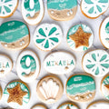 Decorative cookies with beach-themed designs and the name 'MIKAELA'.