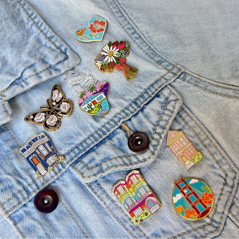 Colorful pins on a denim jacket against a pink background